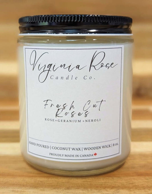 Jar with black lid. It has a label with Virginia Rose Candle Co. Logo printed on it. The candle scent is Fresh Cut Roses.
